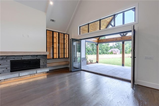 unfurnished living room with hardwood / wood-style flooring, a stone fireplace, and high vaulted ceiling