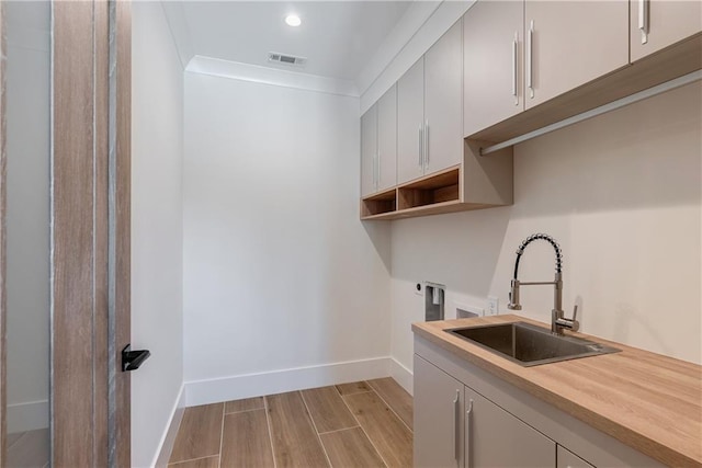 clothes washing area featuring sink, cabinets, washer hookup, hookup for an electric dryer, and crown molding