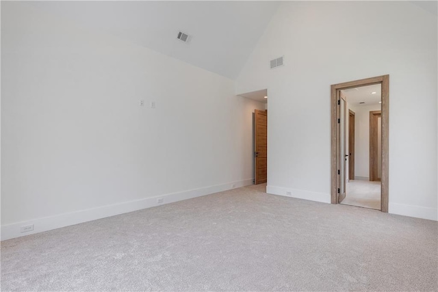 carpeted empty room with high vaulted ceiling