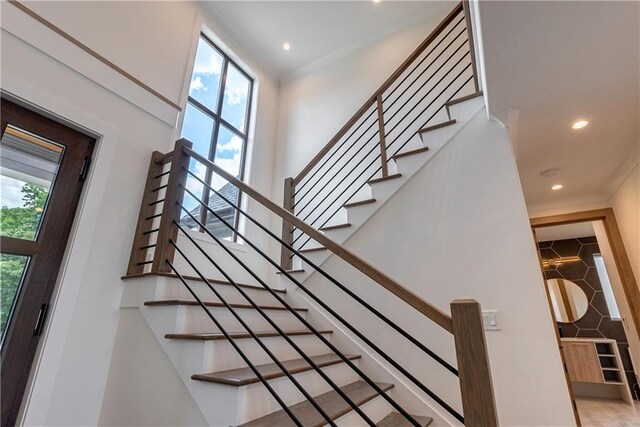 stairway with a wealth of natural light and crown molding