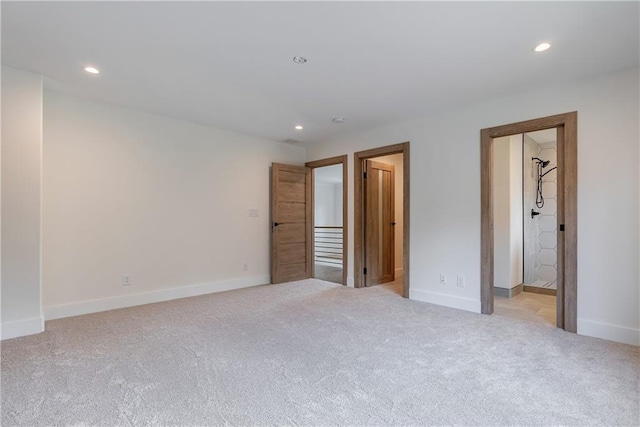 unfurnished bedroom with ensuite bathroom and light colored carpet