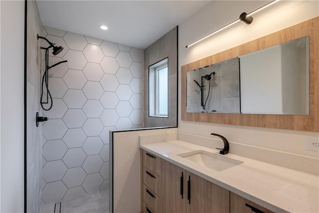 bathroom featuring a shower, vanity, and tile walls