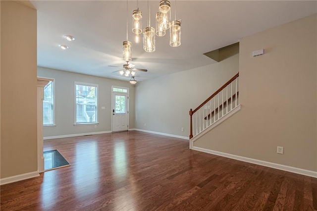 interior space with ceiling fan with notable chandelier and dark wood-type flooring