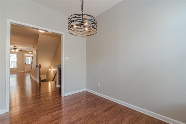 empty room with dark hardwood / wood-style floors and ceiling fan with notable chandelier