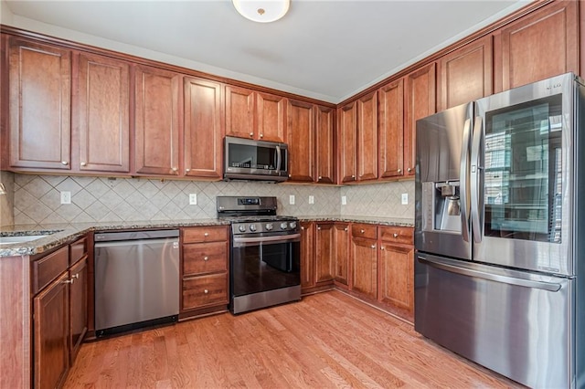 kitchen with light stone countertops, sink, light hardwood / wood-style floors, decorative backsplash, and appliances with stainless steel finishes