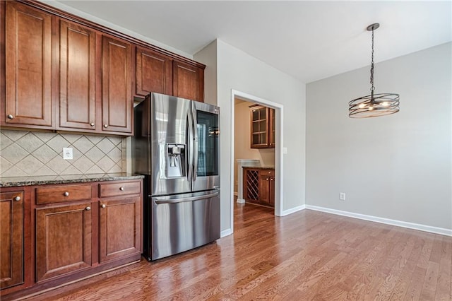 kitchen with decorative backsplash, stainless steel fridge with ice dispenser, a chandelier, and hardwood / wood-style floors