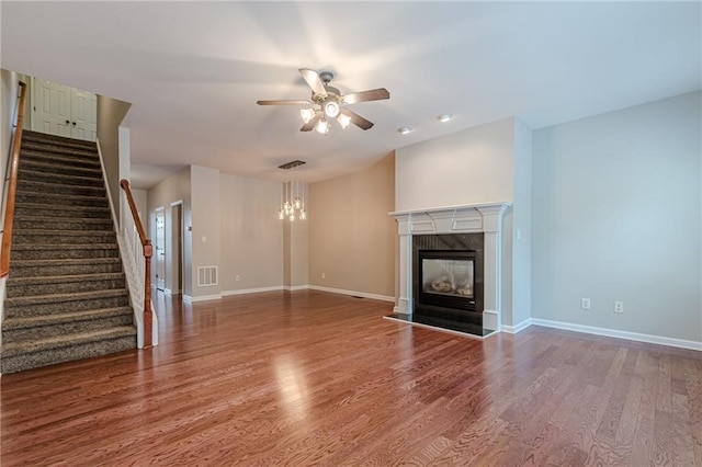 unfurnished living room featuring a premium fireplace, ceiling fan, and wood-type flooring