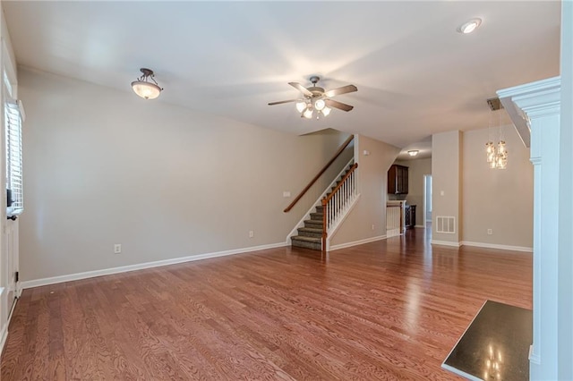 unfurnished living room with ceiling fan with notable chandelier and hardwood / wood-style flooring