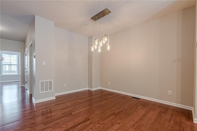 empty room featuring dark hardwood / wood-style floors and a chandelier