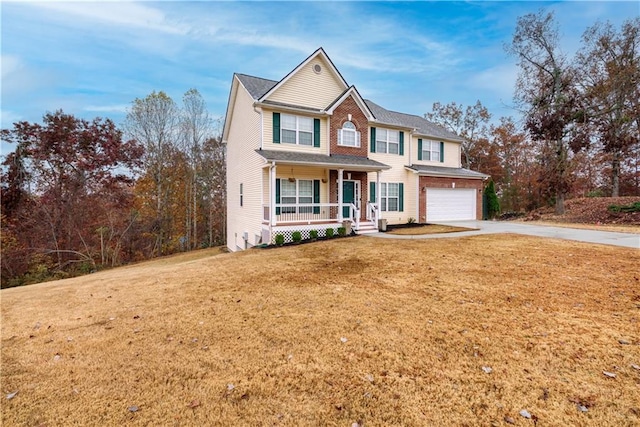 view of front of home with covered porch, a garage, and a front yard