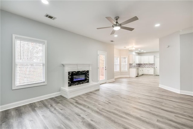 unfurnished living room with light hardwood / wood-style floors, ceiling fan, and a tiled fireplace