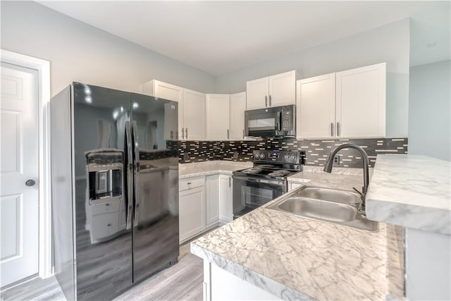 kitchen with kitchen peninsula, sink, black appliances, light hardwood / wood-style floors, and white cabinetry