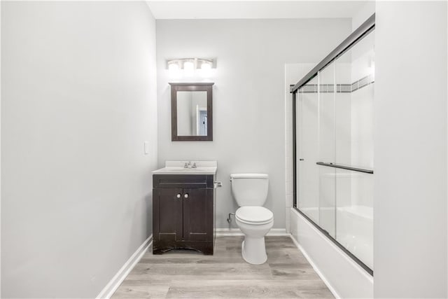 full bathroom with hardwood / wood-style floors, vanity, toilet, and enclosed tub / shower combo