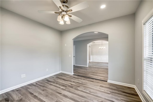 empty room with hardwood / wood-style flooring and ceiling fan with notable chandelier