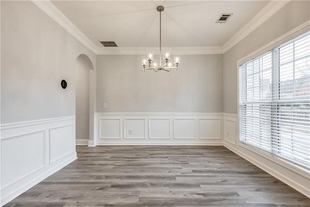 unfurnished dining area with hardwood / wood-style floors, ornamental molding, and an inviting chandelier