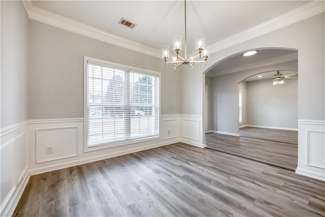 unfurnished dining area featuring hardwood / wood-style floors, ceiling fan with notable chandelier, and crown molding