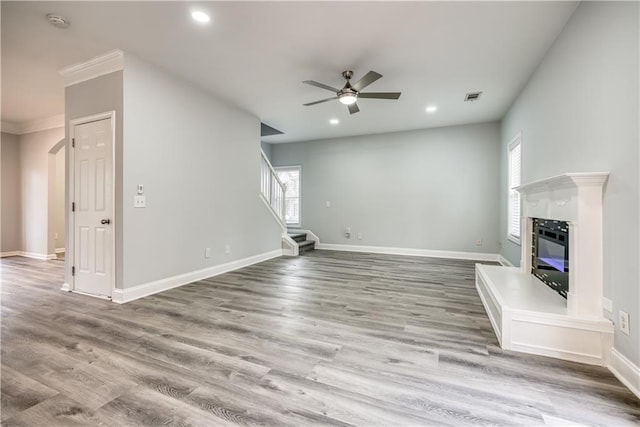 unfurnished living room with ceiling fan, hardwood / wood-style floors, and crown molding