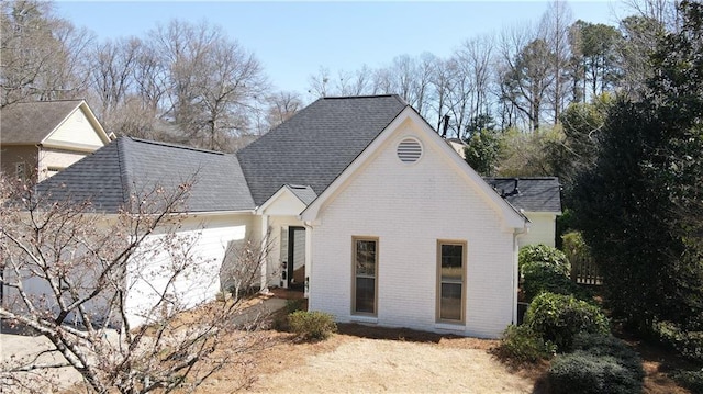 view of property exterior with brick siding and roof with shingles