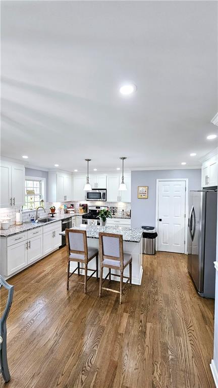 kitchen featuring hanging light fixtures, light stone countertops, a kitchen island, and appliances with stainless steel finishes