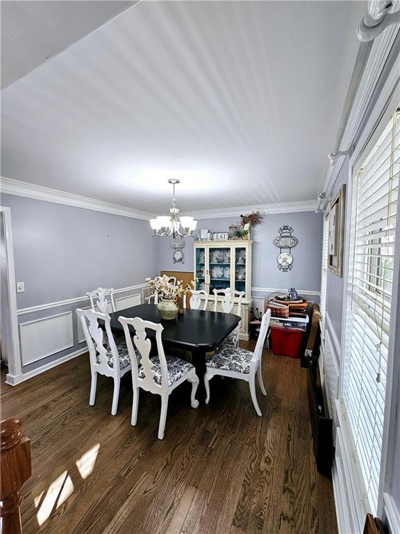 dining room featuring a notable chandelier, ornamental molding, and dark hardwood / wood-style floors