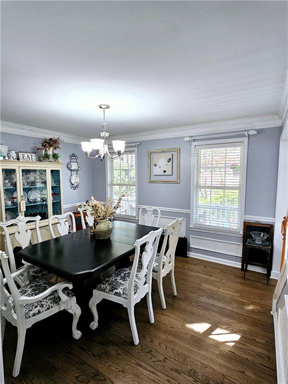 dining area featuring crown molding, dark hardwood / wood-style floors, and a chandelier