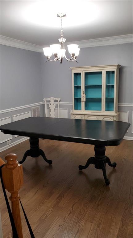 dining area featuring crown molding, wood-type flooring, and a chandelier