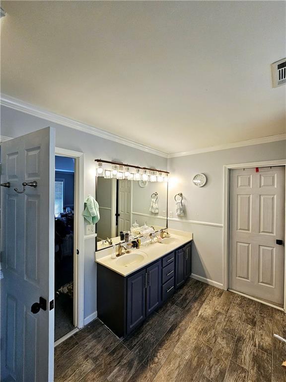 bathroom with hardwood / wood-style flooring, ornamental molding, and vanity