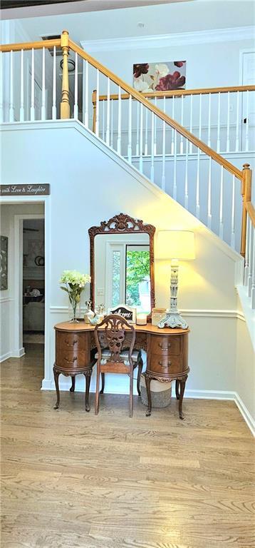 staircase with hardwood / wood-style flooring, ornamental molding, and a high ceiling