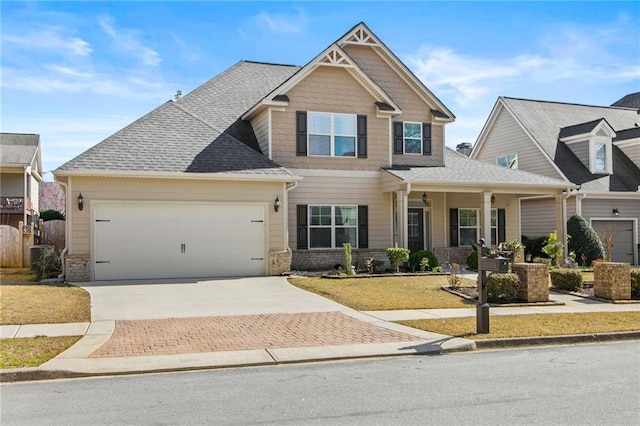 craftsman-style house featuring decorative driveway, brick siding, an attached garage, and a shingled roof