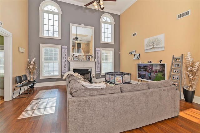 living room with crown molding, ceiling fan, hardwood / wood-style floors, and a high ceiling