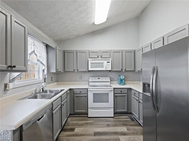 kitchen featuring lofted ceiling, sink, a textured ceiling, appliances with stainless steel finishes, and dark hardwood / wood-style floors