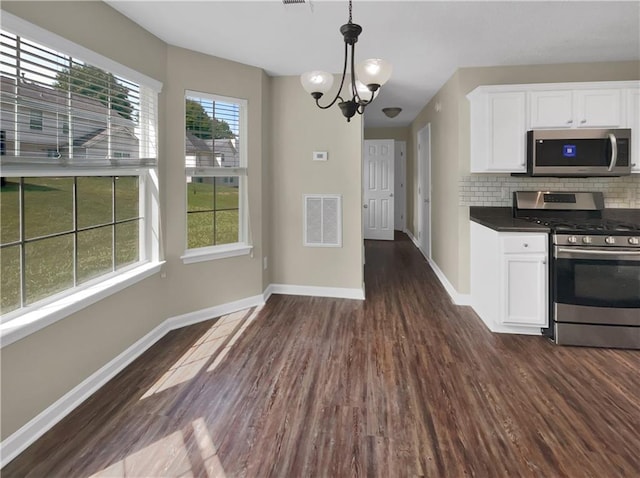 kitchen featuring appliances with stainless steel finishes, dark hardwood / wood-style floors, an inviting chandelier, and pendant lighting