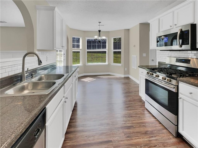 kitchen with appliances with stainless steel finishes, dark wood-type flooring, sink, white cabinetry, and a chandelier