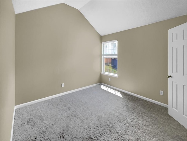 carpeted spare room with baseboards and lofted ceiling