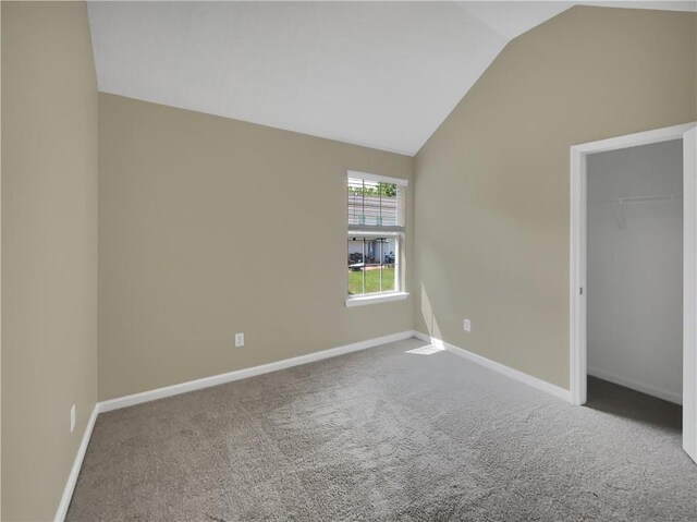 carpeted empty room with lofted ceiling