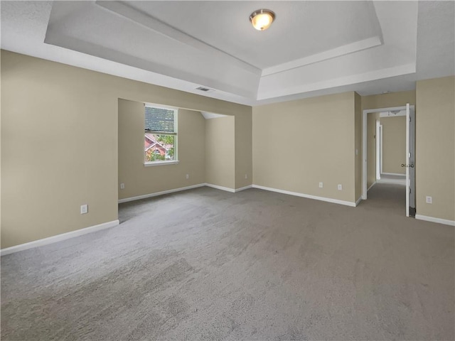 spare room with baseboards, a raised ceiling, and carpet