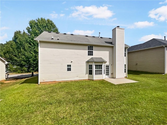 rear view of property with a lawn, a chimney, and a patio area