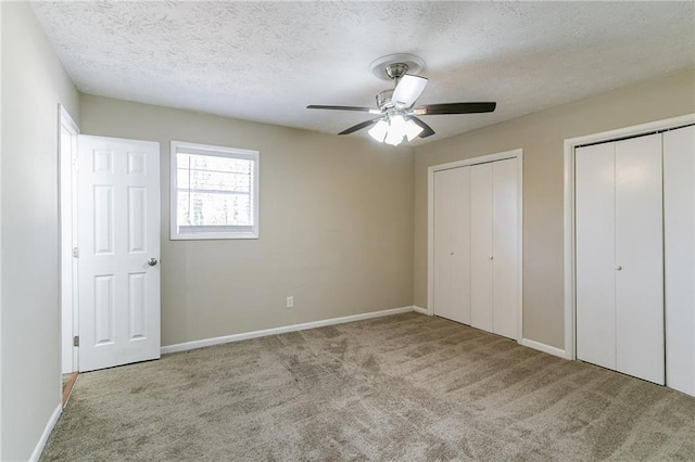 8775 Lee Rd, Lithia Springs, GA 30122 - unfurnished bedroom with a textured ceiling, ceiling fan, light carpet, and two closets