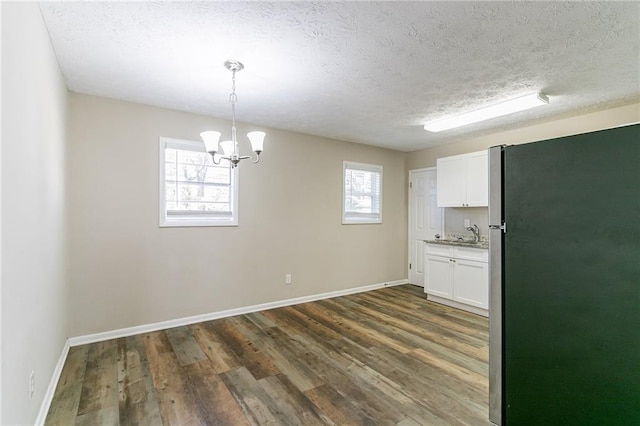 8775 Lee Rd, Lithia Springs, GA 30122 - unfurnished dining area with a textured ceiling, dark wood-type flooring, a healthy amount of sunlight, and a notable chandelier