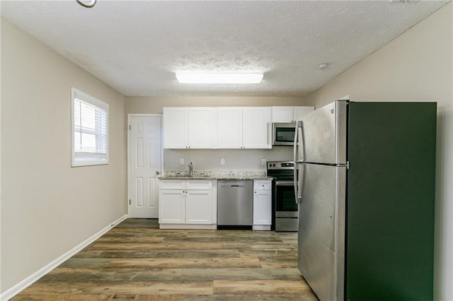 8775 Lee Rd, Lithia Springs, GA 30122 - kitchen featuring sink, hardwood / wood-style flooring, a textured ceiling, white cabinetry, and stainless steel appliances