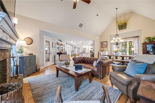 living area with a brick fireplace, light wood-type flooring, french doors, high vaulted ceiling, and a ceiling fan