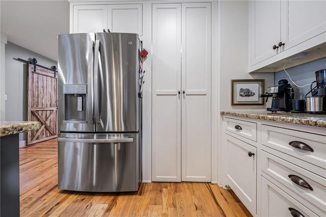 kitchen with white cabinetry, appliances with stainless steel finishes, wall chimney exhaust hood, and light wood finished floors