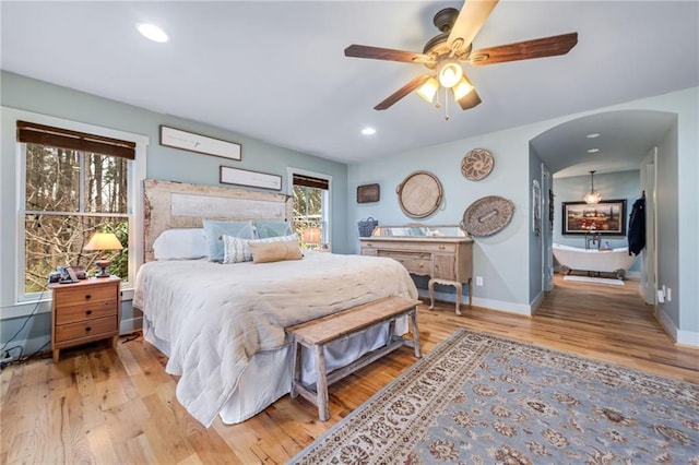 bedroom featuring a ceiling fan, baseboards, light wood-type flooring, recessed lighting, and arched walkways