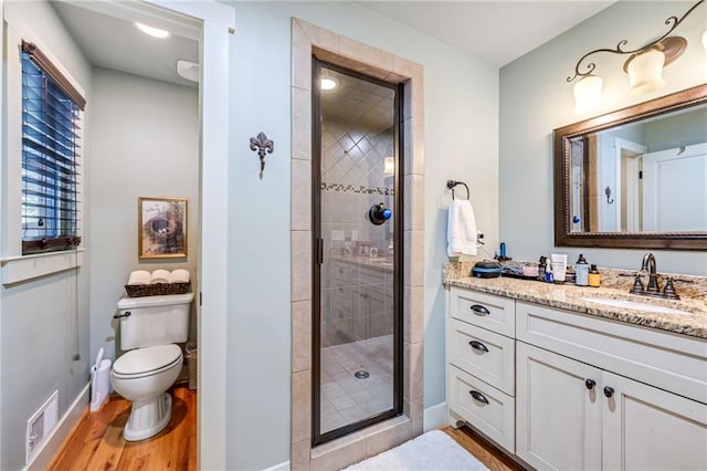 full bath with vanity, baseboards, a shower stall, wood finished floors, and visible vents