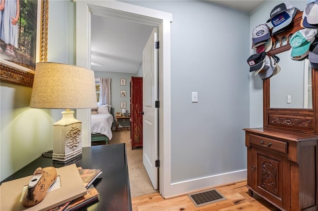 hall with visible vents, light wood-style floors, and baseboards