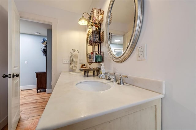 bathroom with a sink, baseboards, double vanity, and wood finished floors