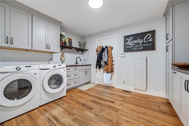 clothes washing area featuring light wood-style floors, cabinet space, washing machine and dryer, and visible vents