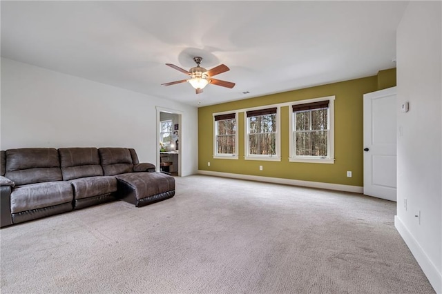 carpeted living area with ceiling fan and baseboards