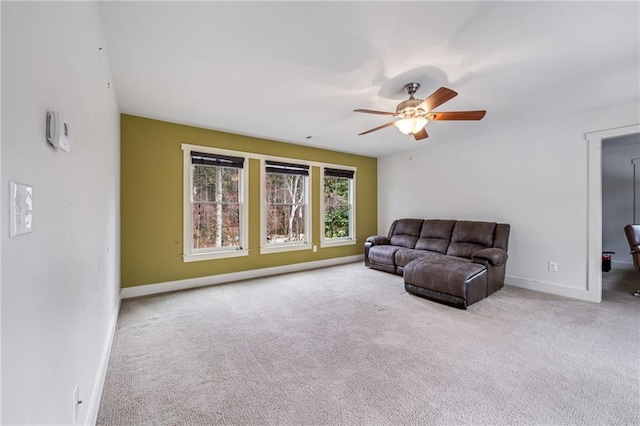 carpeted living area with baseboards and a ceiling fan
