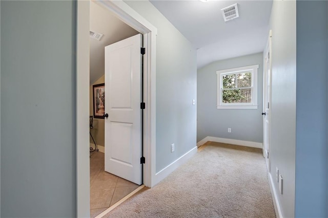 hallway featuring baseboards, light carpet, light tile patterned flooring, and visible vents